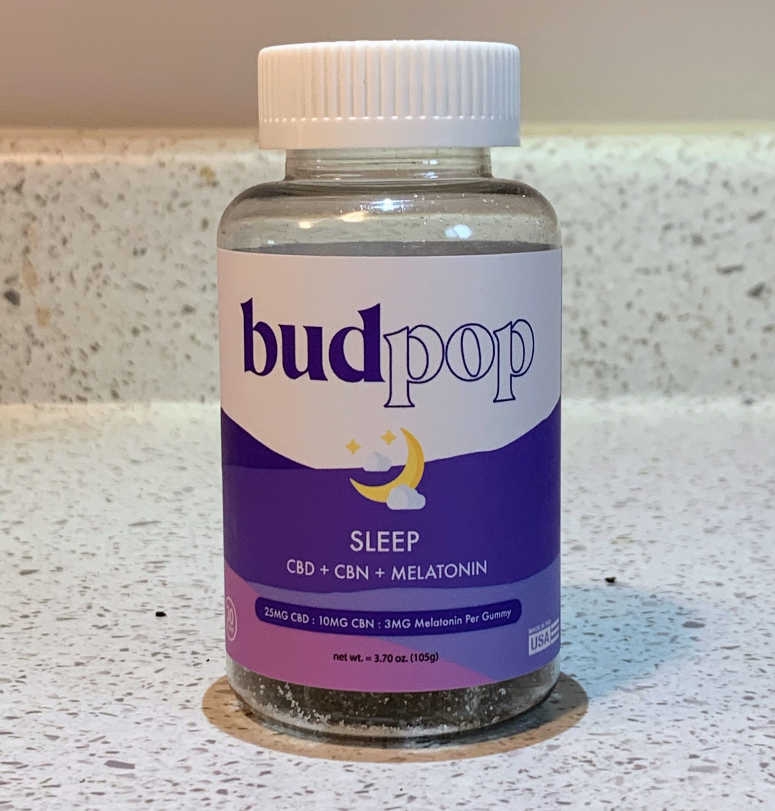 A purple and white bottle of cannabis edibles designed for sleep sits on a white countertop