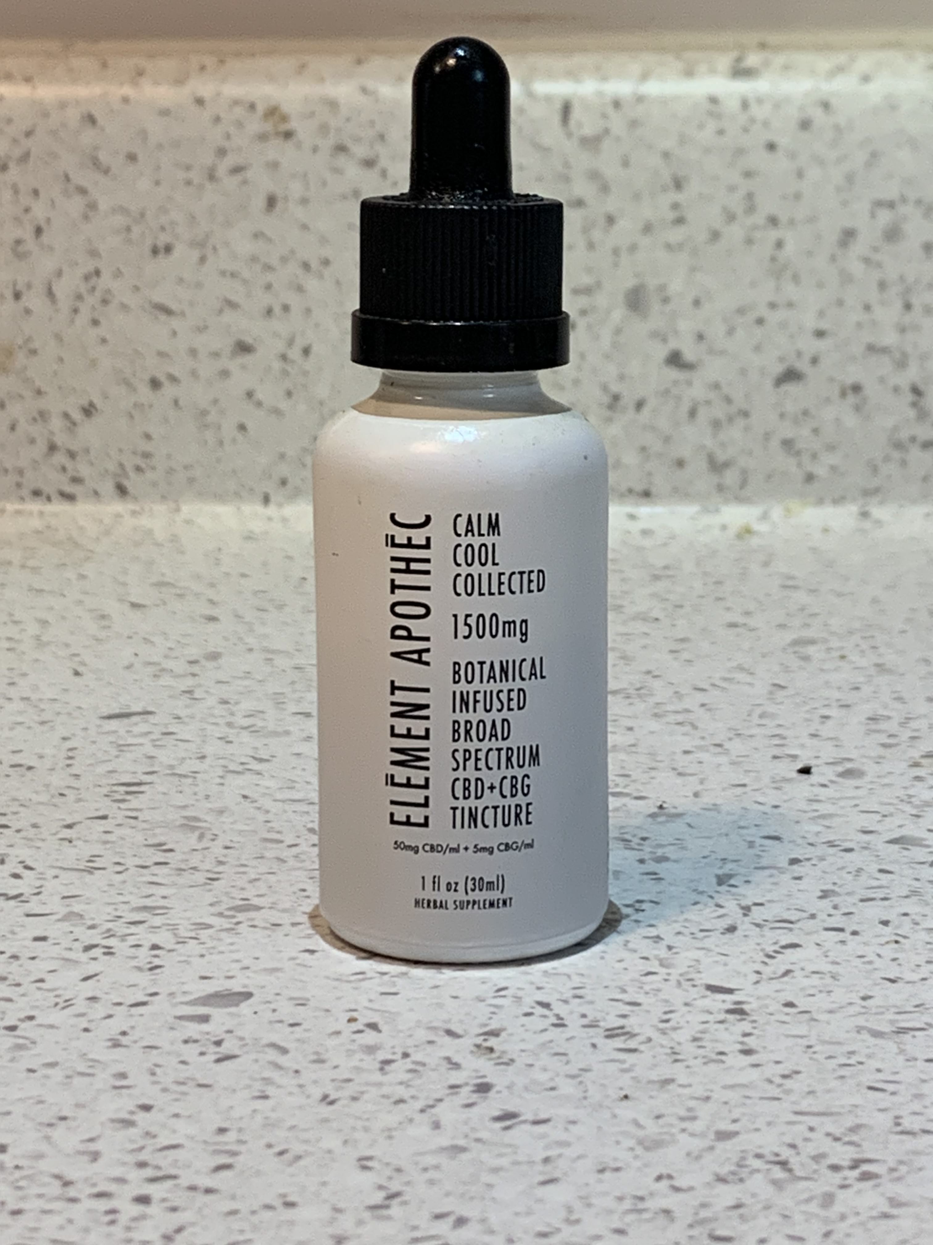 A small white bottle of Element Apothec Cool Calm Collected CBD tincture on a white countertop