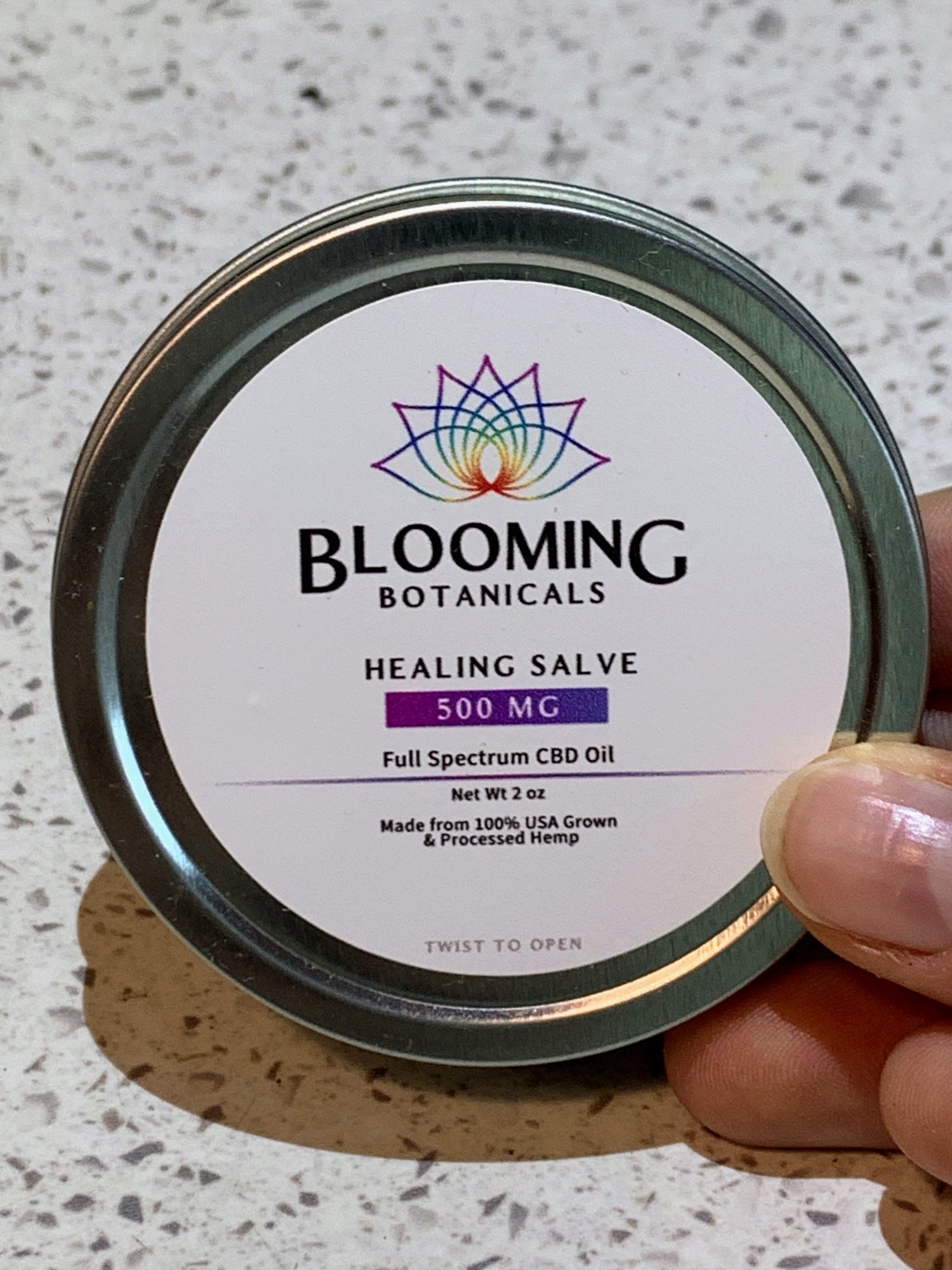 blooming botanicals healing salve held against a white countertop