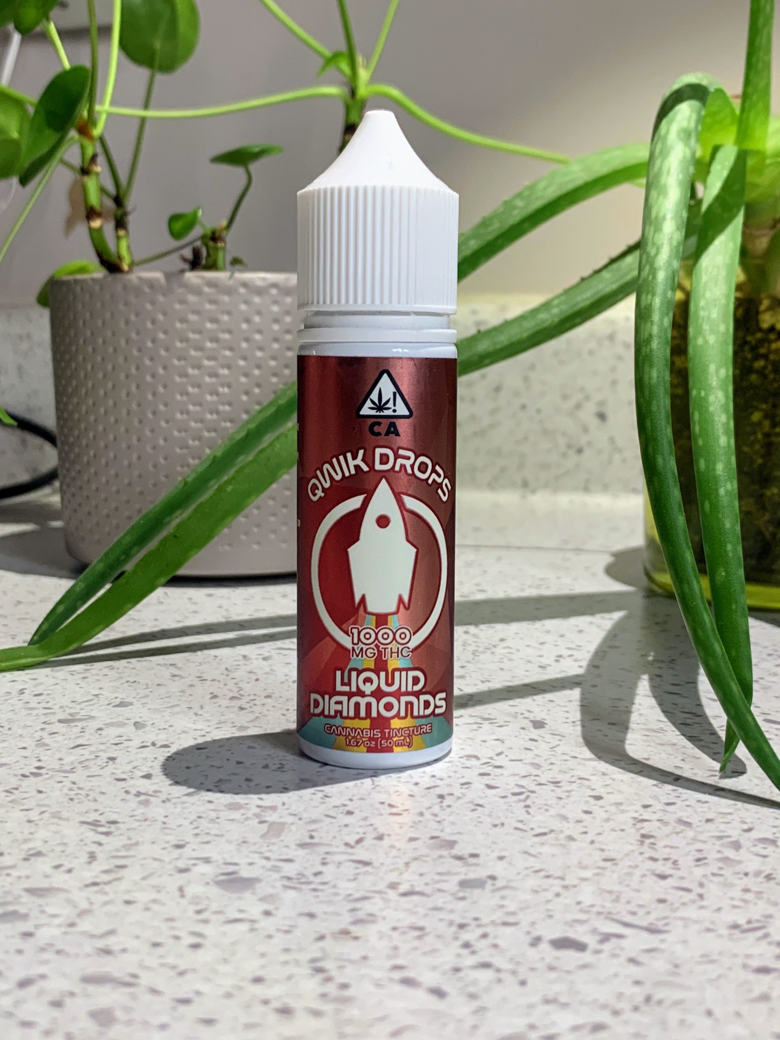 QWIK Liquids QWIK Drops on a white countertop with plants in the background