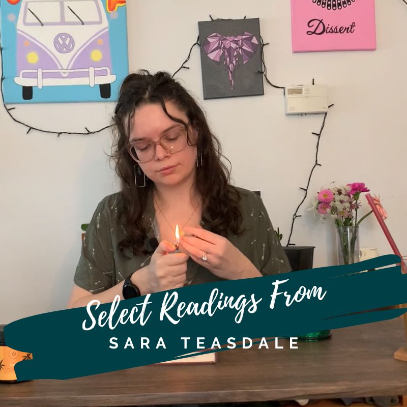 white woman sitting at a desk lights a joint against a white wall with artwork